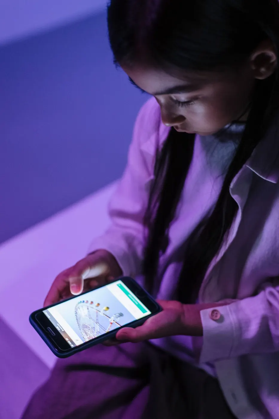 A person using a smartphone in purple neon light