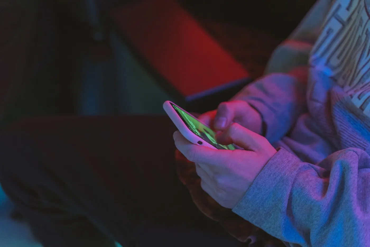 Hands holding a smartphone in neon light