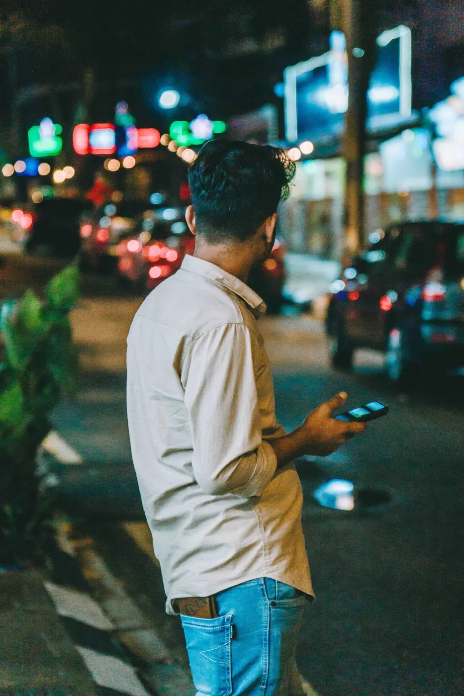 A person using a phone on a city street at night